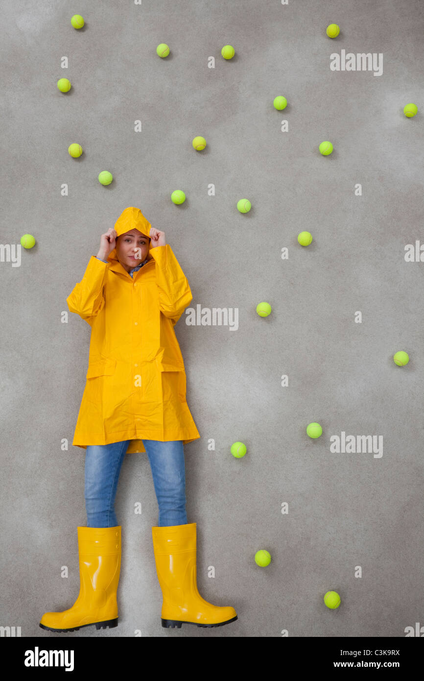 Mid adult woman wearing rain coat and rubber boots in acid rain Stock Photo