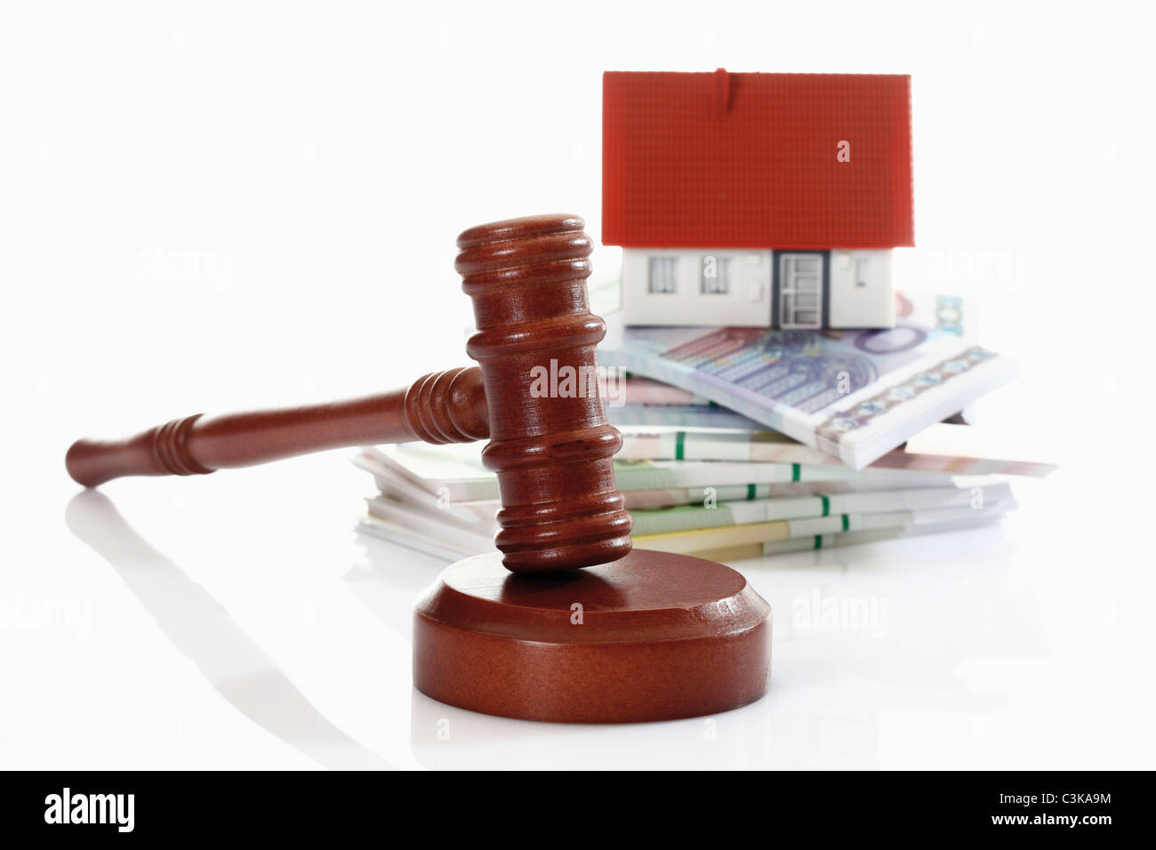 Auction hammer with model household and wad of notes in background