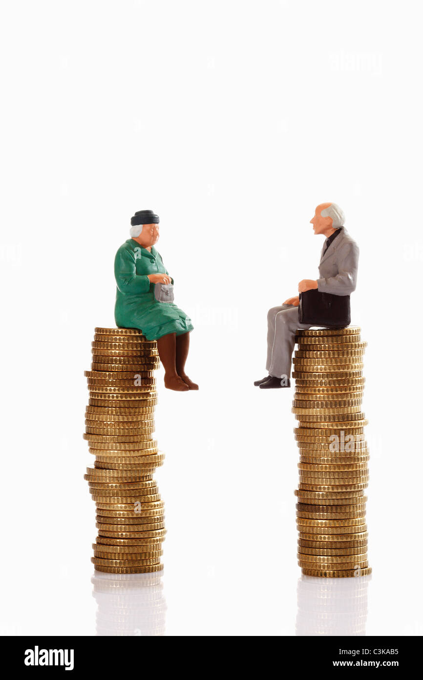Figurines grandma and grandpa sitting on coin stack Stock Photo