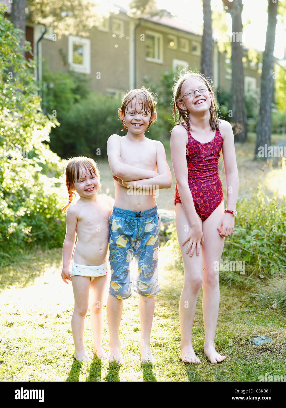 Wet brother and two sister standing in garden Stock Photo - Alamy