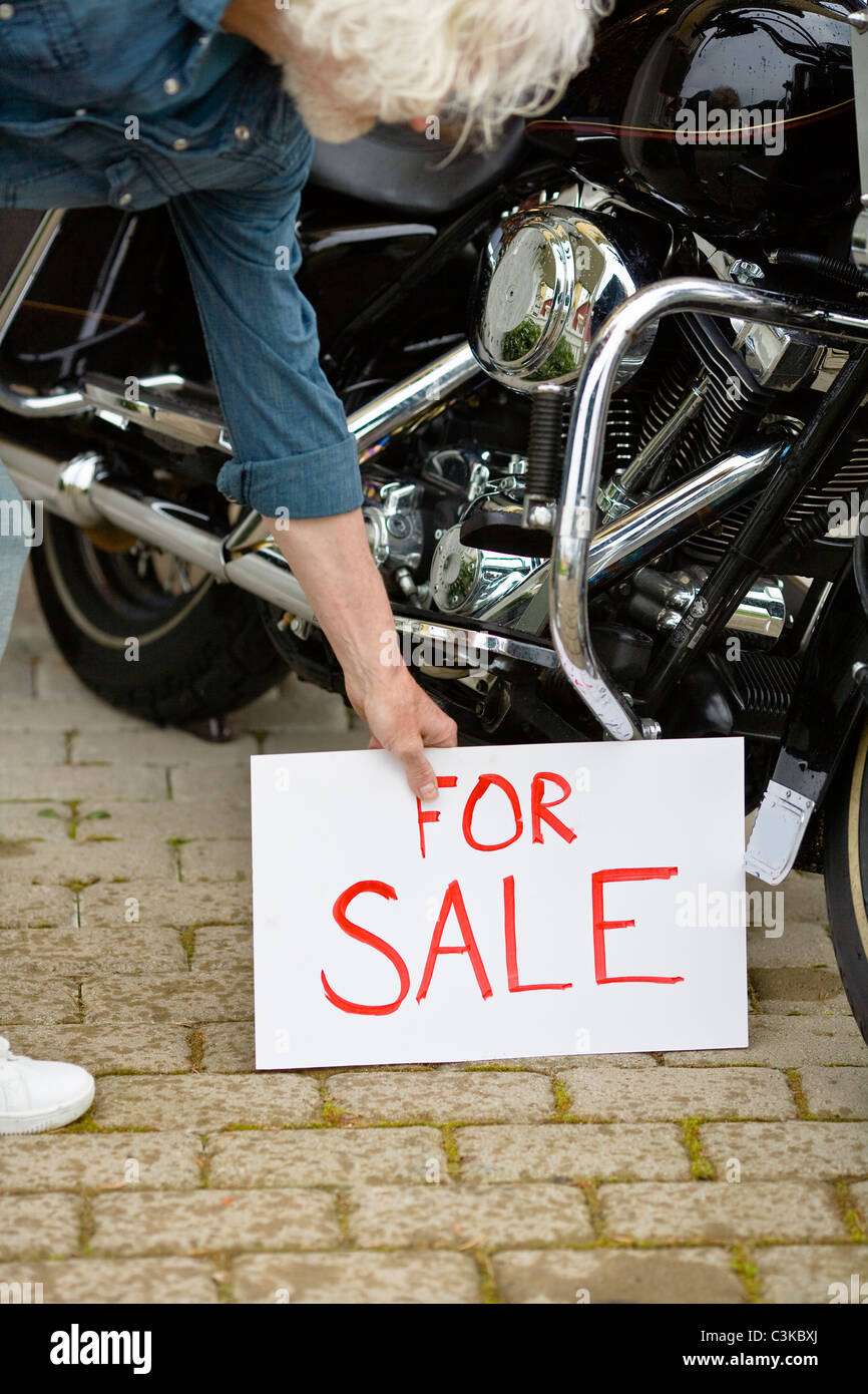 Man putting for sale sign by vintage motorbike Stock Photo