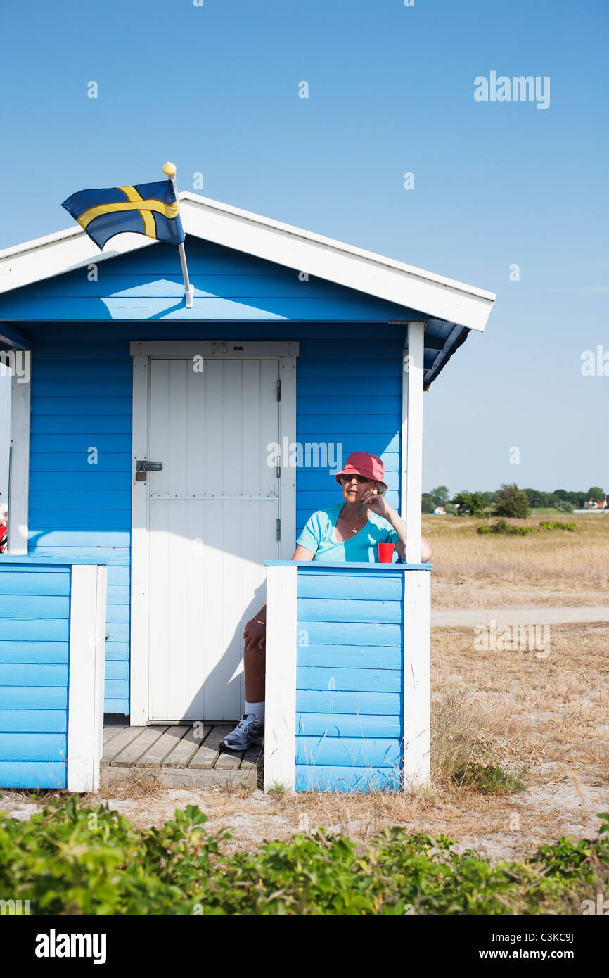 Woman sitting in front of bathing hut on beach Stock Photo