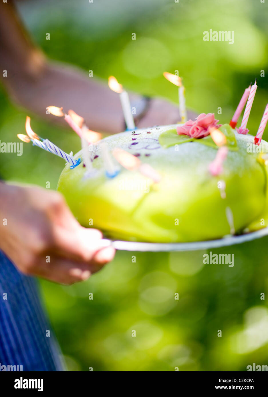 Woman holding birthday cake with lit candles, close-up Stock Photo