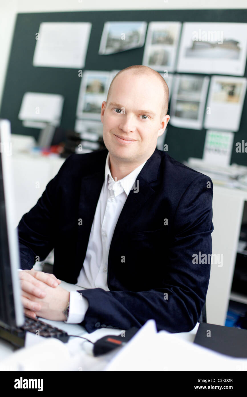 Man sitting in office, smiling Stock Photo - Alamy