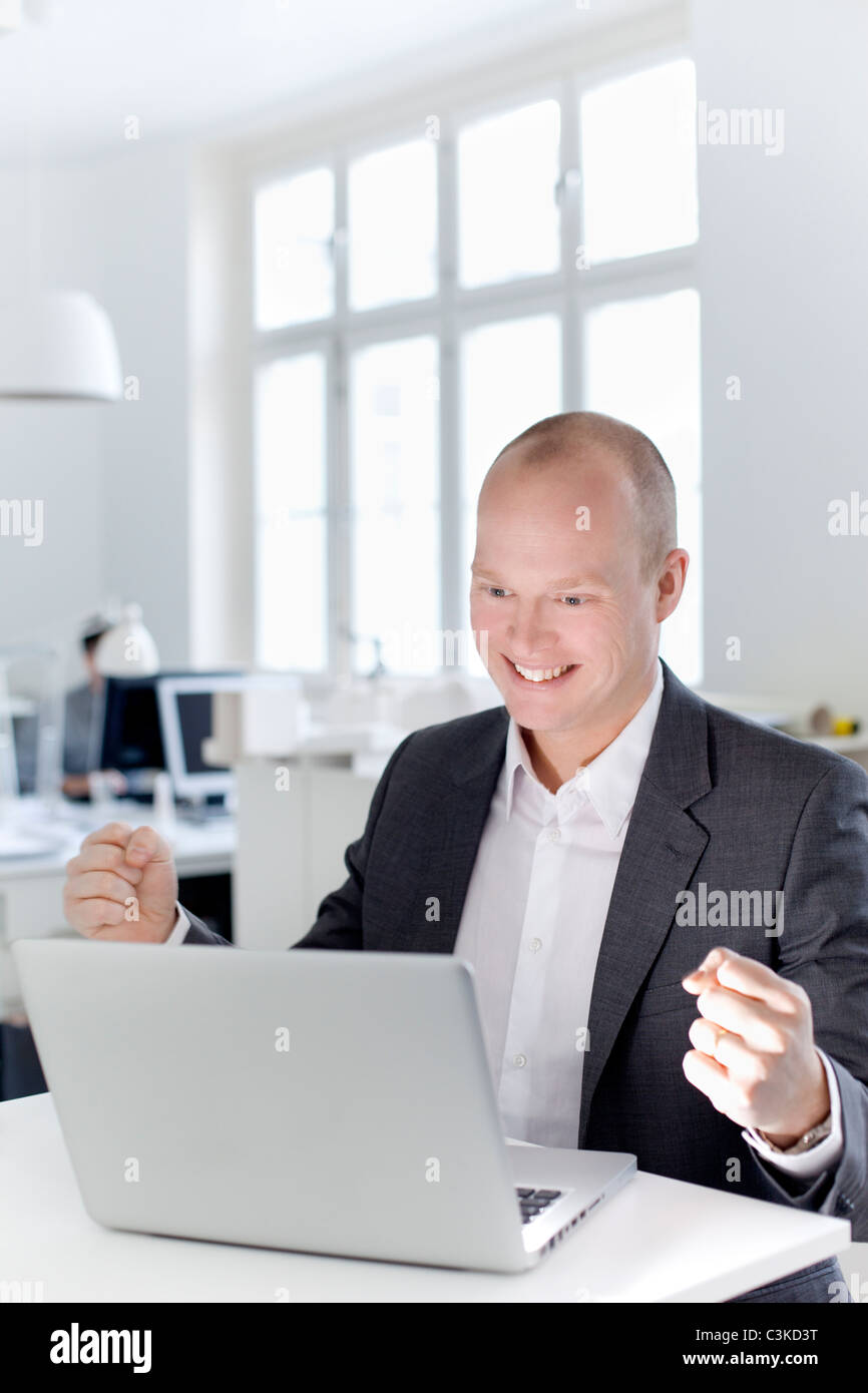 Man looking at laptop and cheering in office Stock Photo