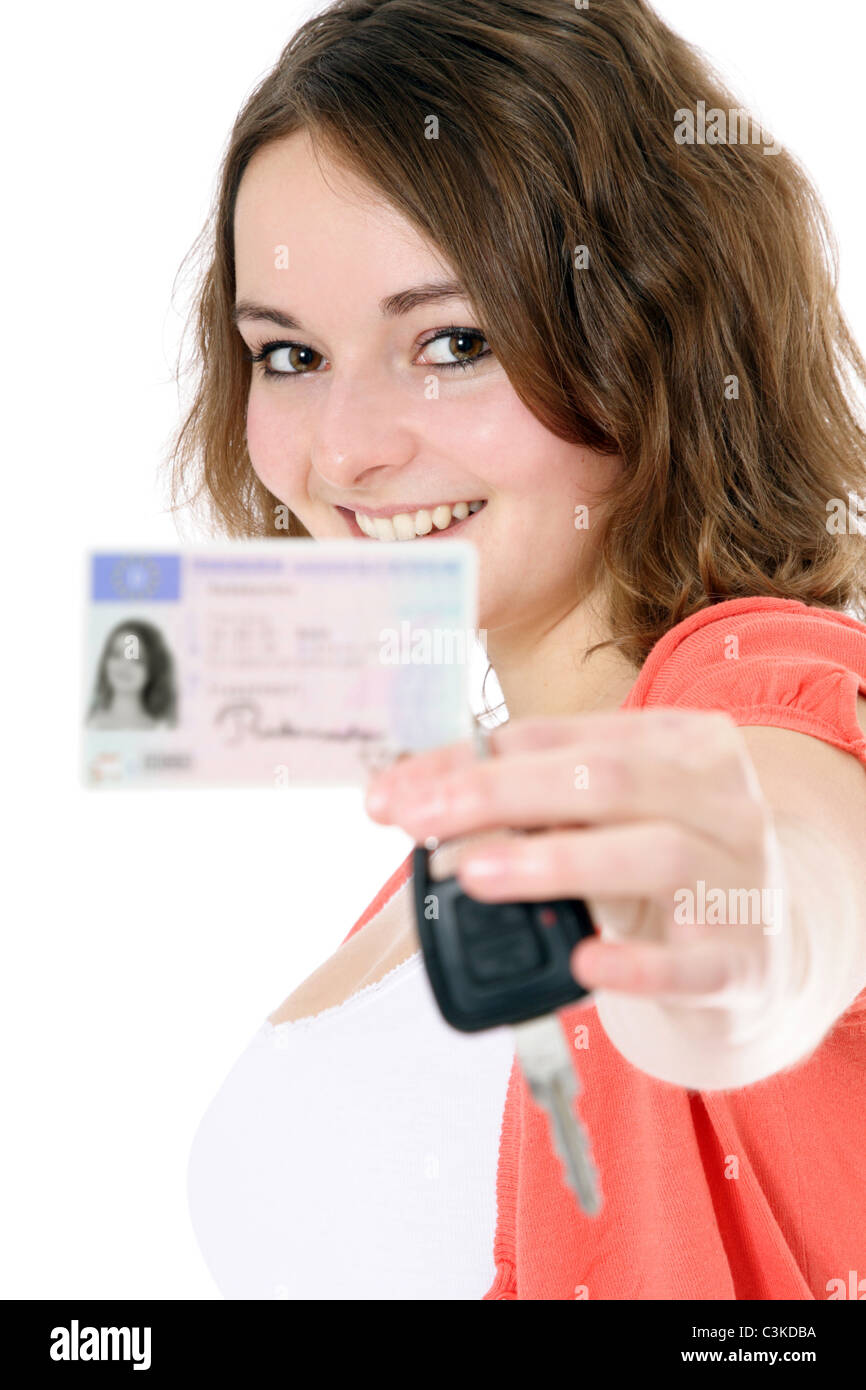 Young woman showing her driver license and car keys. License details blurred out. All on white background. Stock Photo