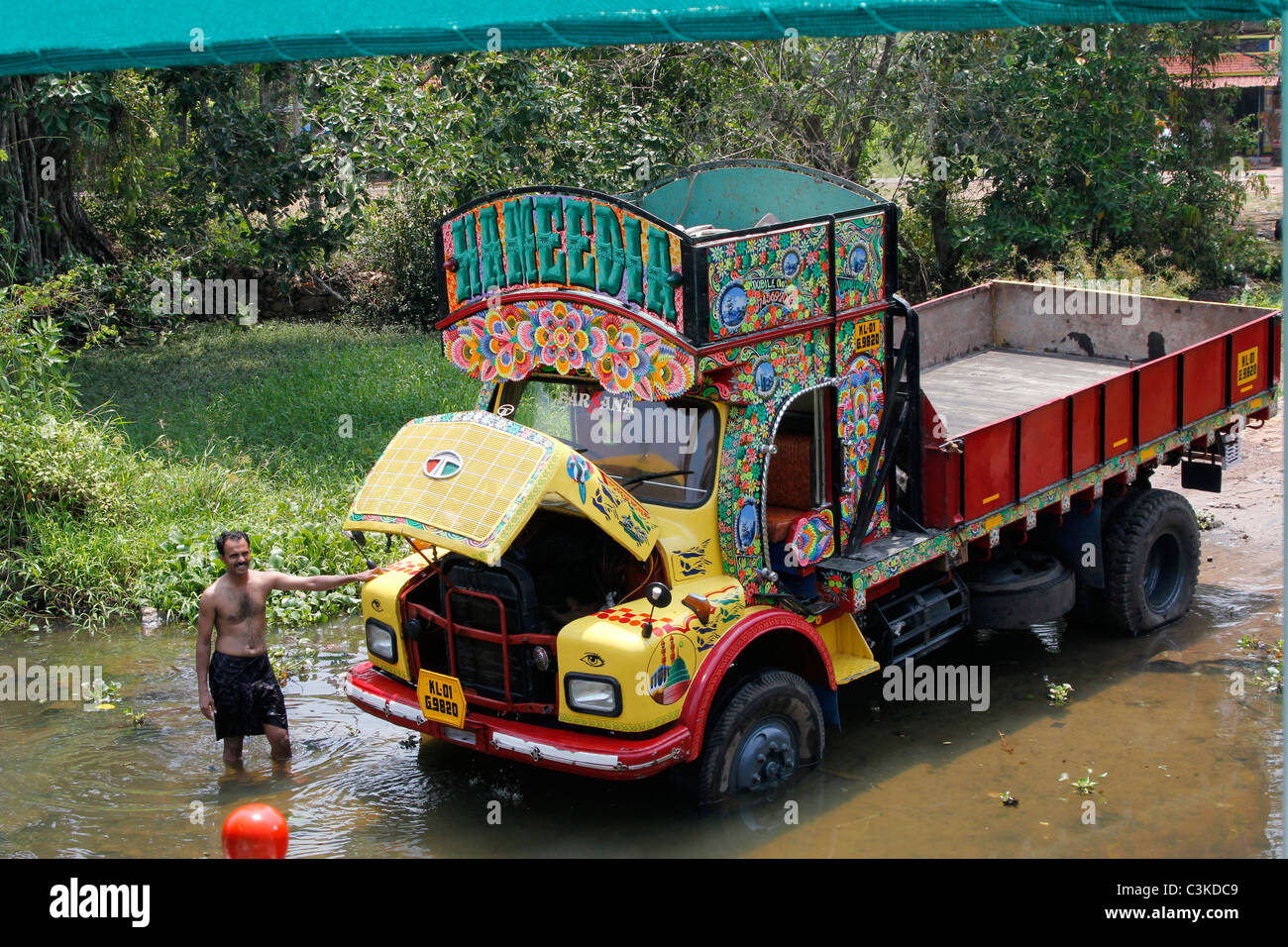 colourful painted truck being washed in a river in the Kerala backwaters in India Stock Photo