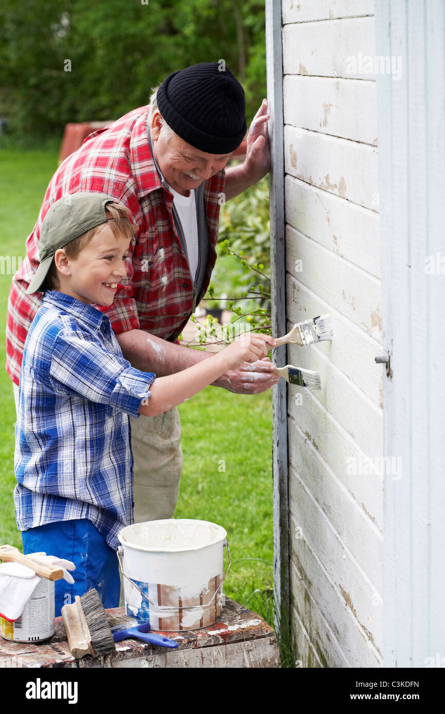 Grandfather and grandson painting their summer cottage, Sweden. Stock Photo