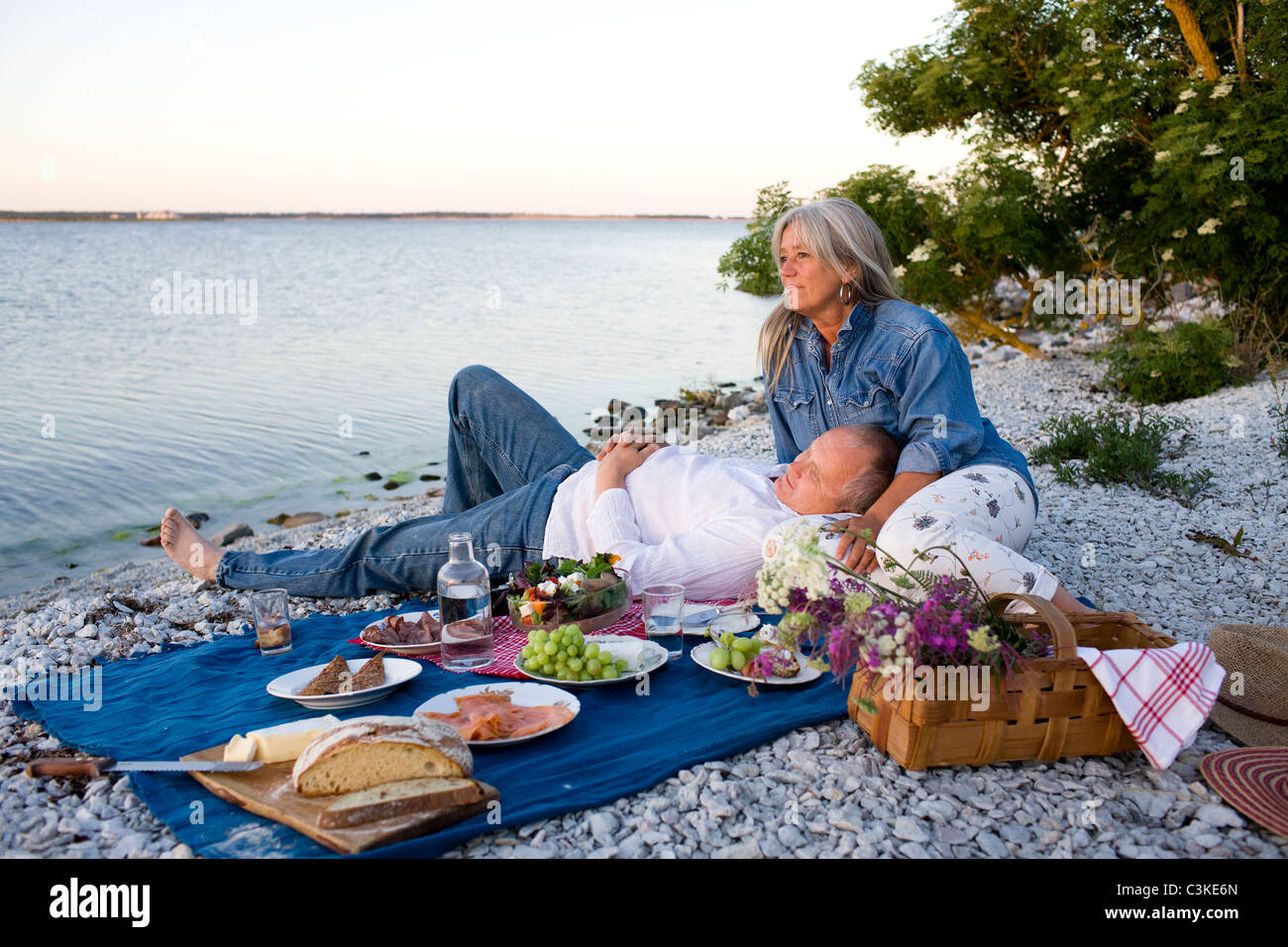 Mature couple having picnic on beach Stock Photo