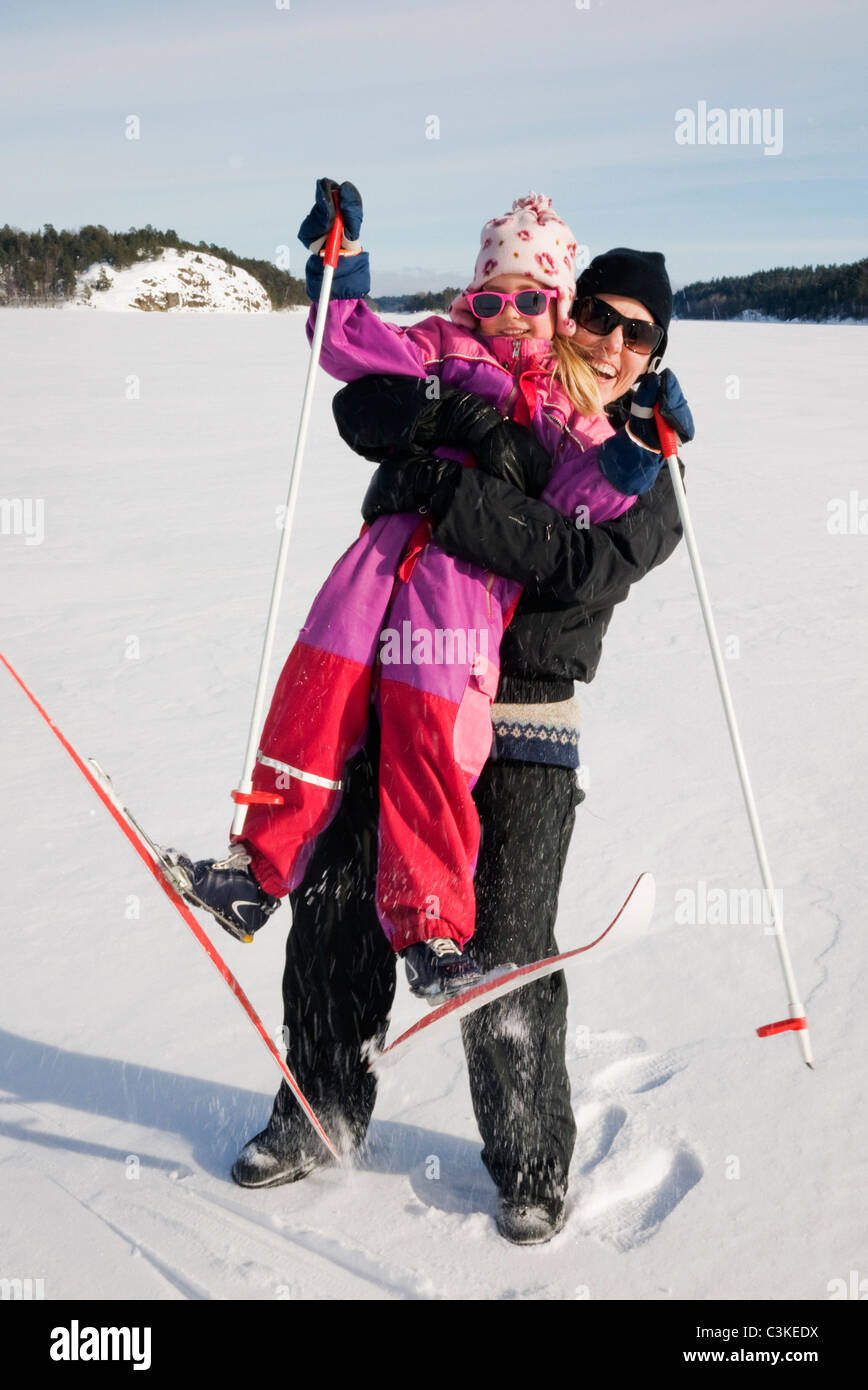 Mother hugging daughter on ski slope Stock Photo