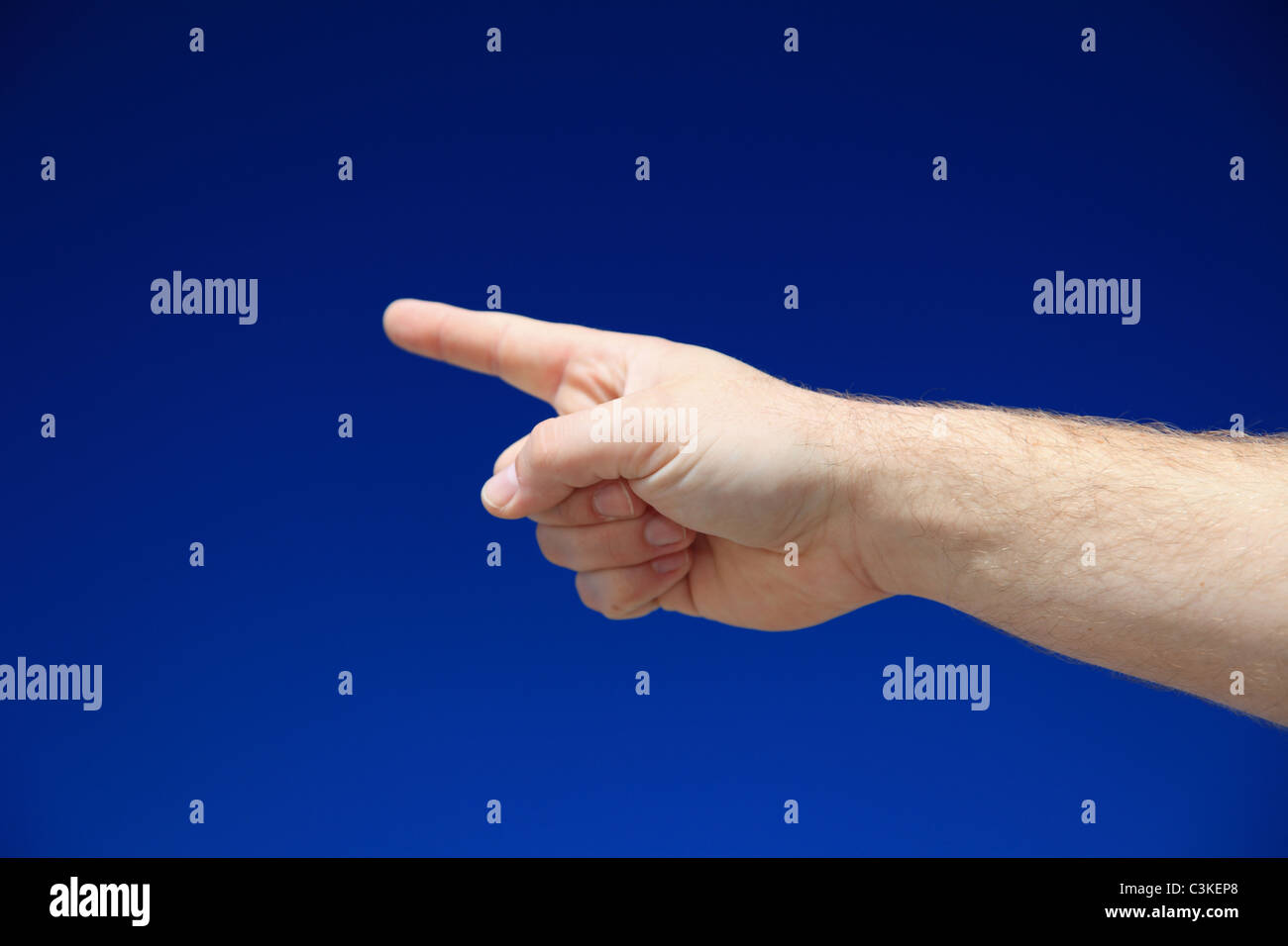 A person pointing with finger in front of bright blue sky. Stock Photo