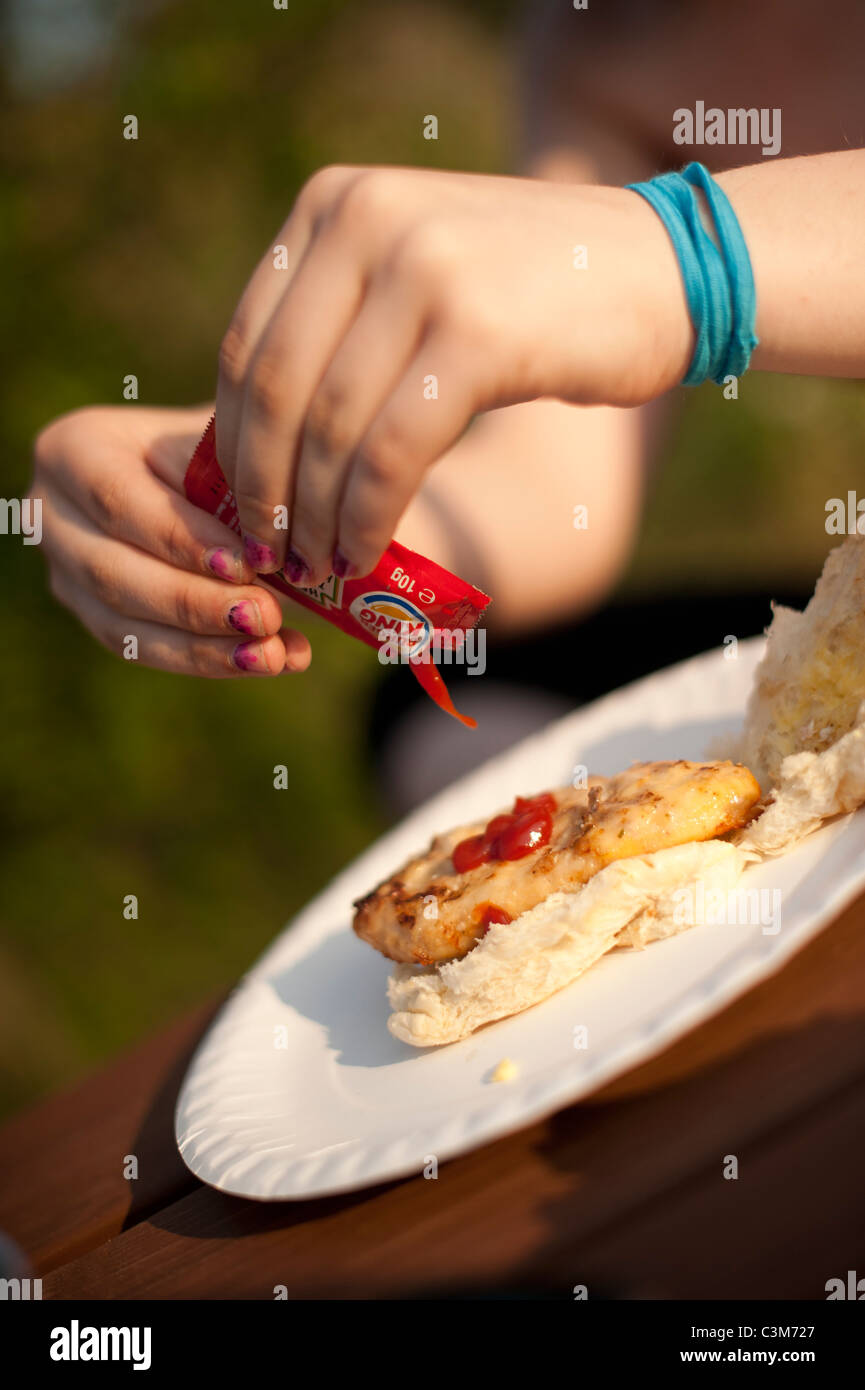 squeezing a sachet of Burger King tomato ketchup on a chicken burger ...