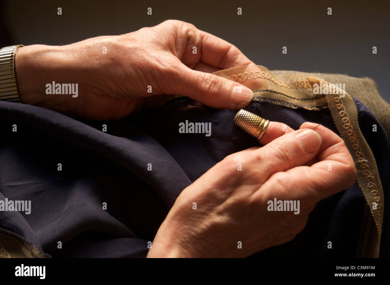 Woman sewing wearing a thimble Stock Photo