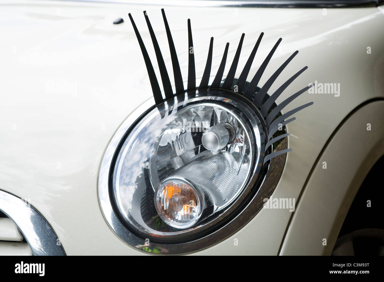 Eye lash / lashes / eyelash / eyelashes attached to a Mini car / car's headlamp / head lamp / headlight / light / lights. Stock Photo