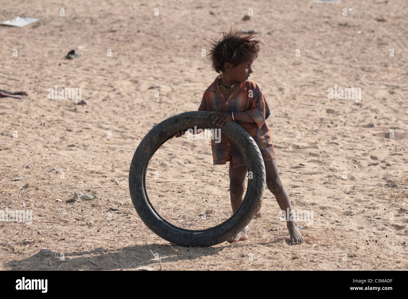 Poor child playing with a tyre in the Thar desert of Rajasthan. Stock Photo