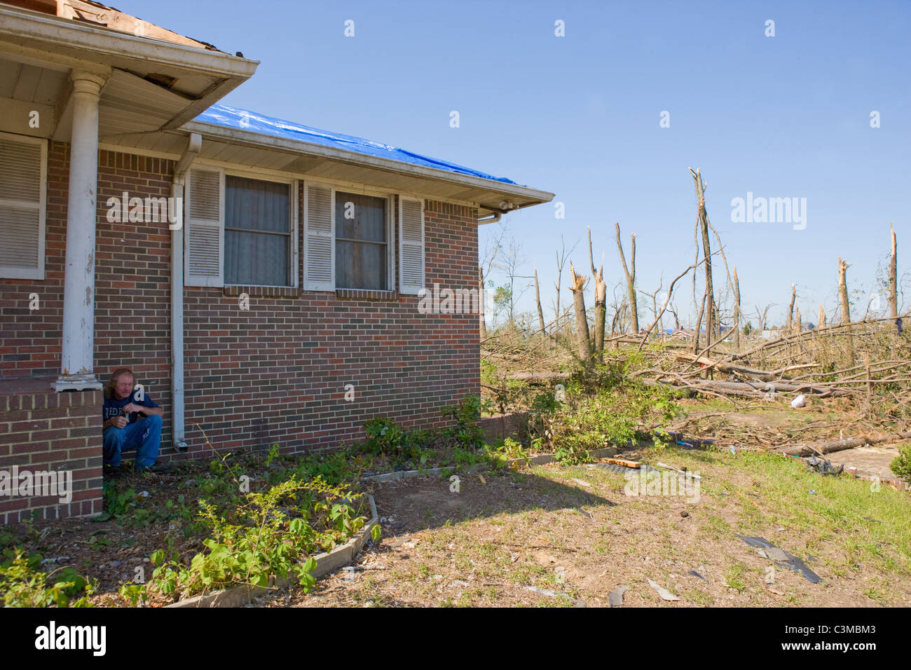 Man demonstrates where he hid when tornado struck his neighborhood, squatting down next to his porch, saved his life. Stock Photo