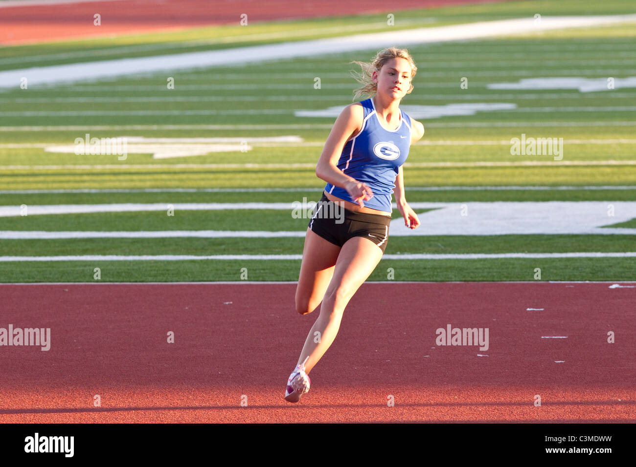 Anglo female athlete approaches high jump bar at high school track meet in San Antonio Texas Stock Photo