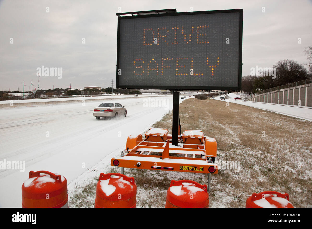 A road sign on a highway in Austin Texas tells motorists to drive safely during a rare winter snowstorm Stock Photo