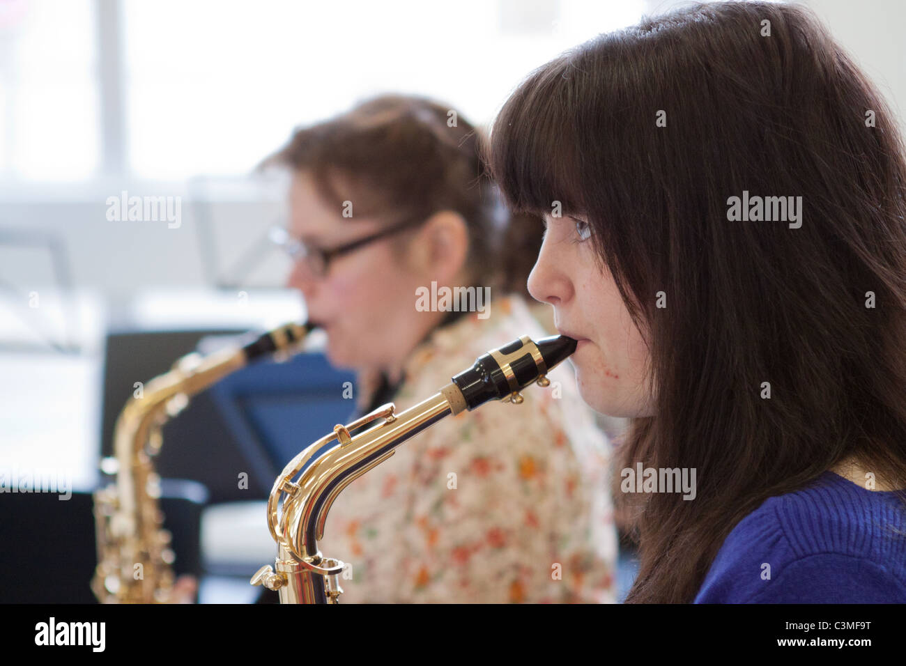 Two saxophonists playing their alto saxophones in  a youth music group / orchestra / band to illustrate article on music, orchestras, youth, etc. Stock Photo