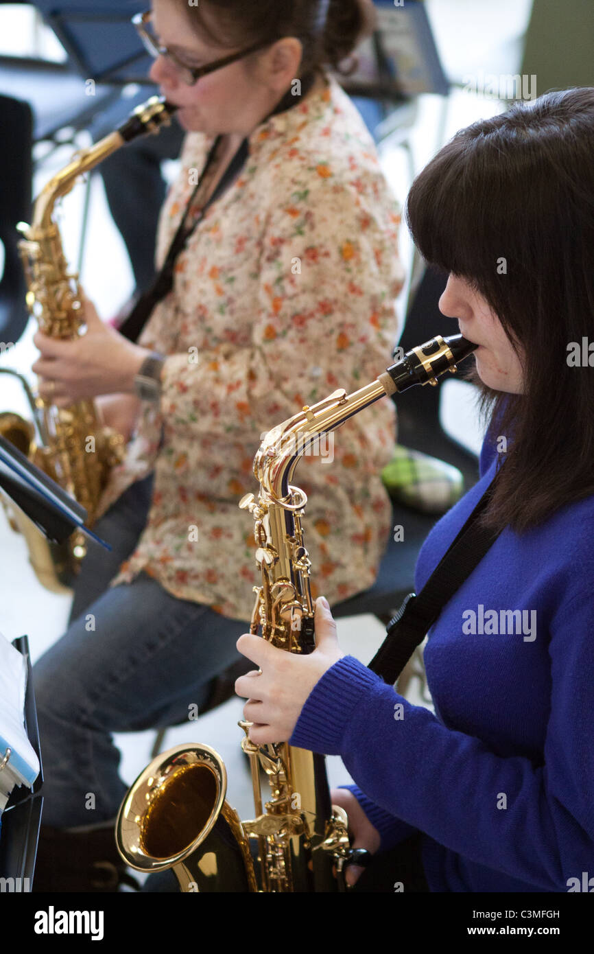 Two saxophonists playing their alto saxophones in  a youth music group / orchestra / band to illustrate article on music, orchestras, youth, etc. Stock Photo