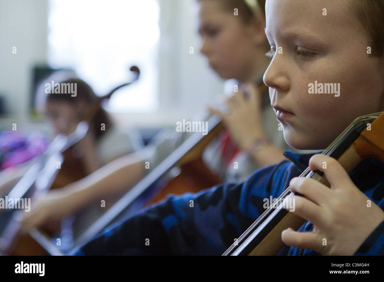 Young cellists playing their cellos in a youth music group / orchestra / band Stock Photo