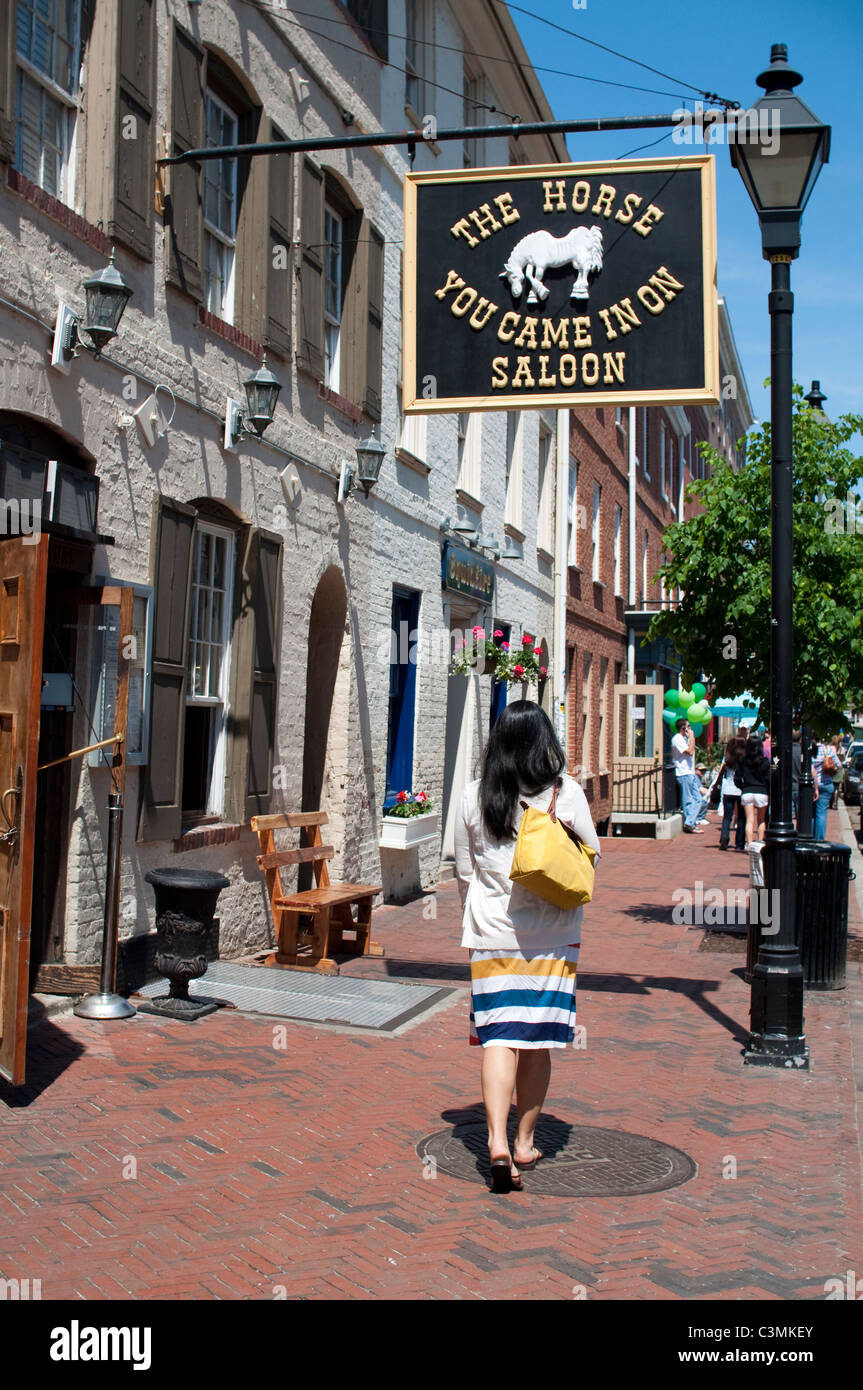 A young woman walks by The Horse You Came In On Saloon in the Fells Point neighborhood of Baltimore, Maryland, USA. Stock Photo