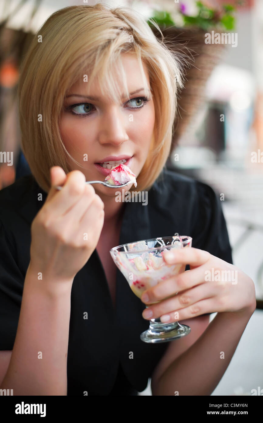 Young woman eating an ice cream at sidewalk cafe Stock Photo