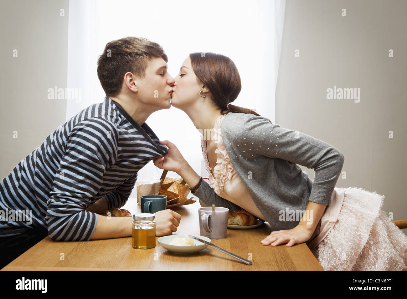 Woman kissing boyfriend over table Stock Photo - Alamy