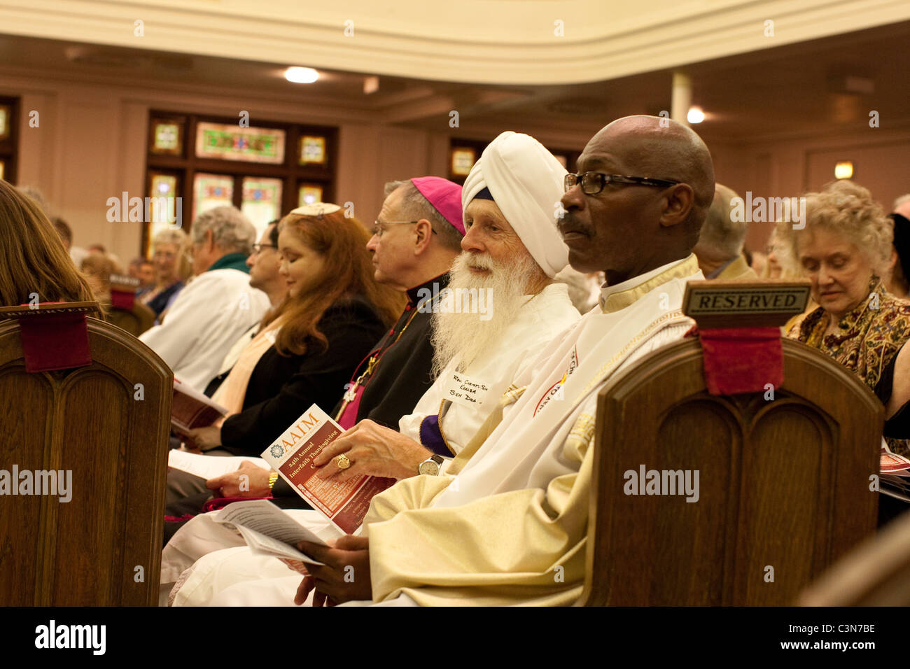 Religious leaders of various faiths and ethnic backgrounds and nationalities sit together in a pew at a Methodist church Stock Photo