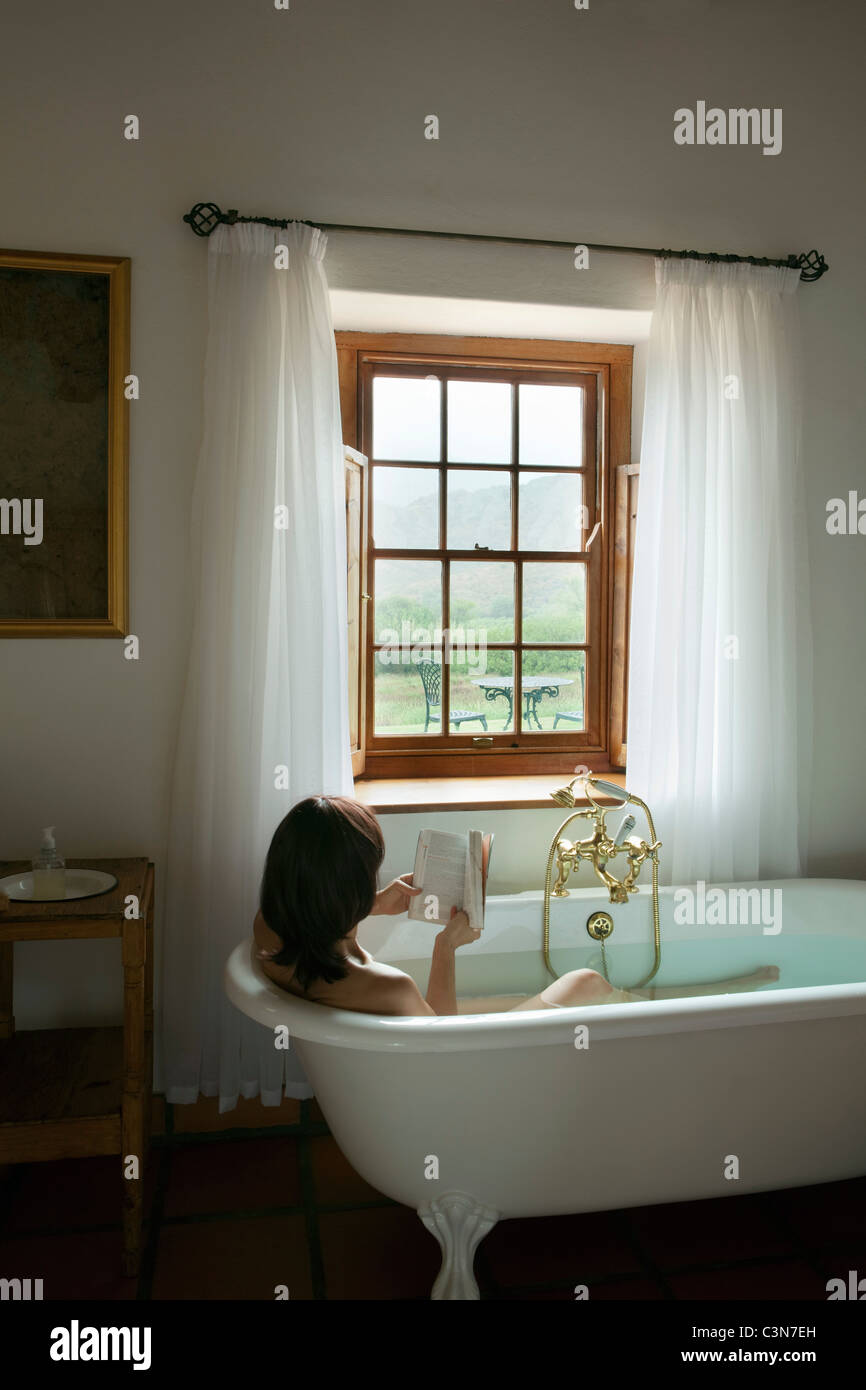 South Africa, Western Cape, Calitzdorp, Red Mountain Nature Reserve. Woman in bath, reading book. Stock Photo