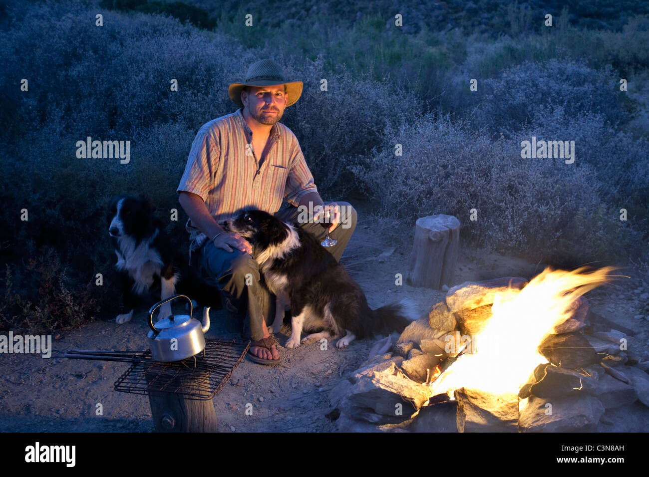 Western Cape, Montagu, Simonskloof Mountain Retreat Owner and host Jurgen Wohlfarter and dog relaxing near campfire Stock Photo