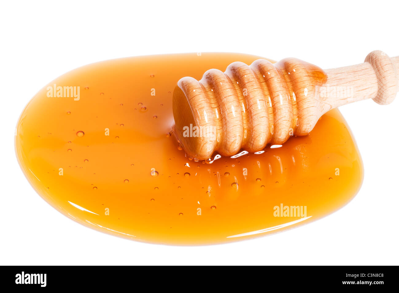 honey dipper from slightly top in a puddle of honey on white background