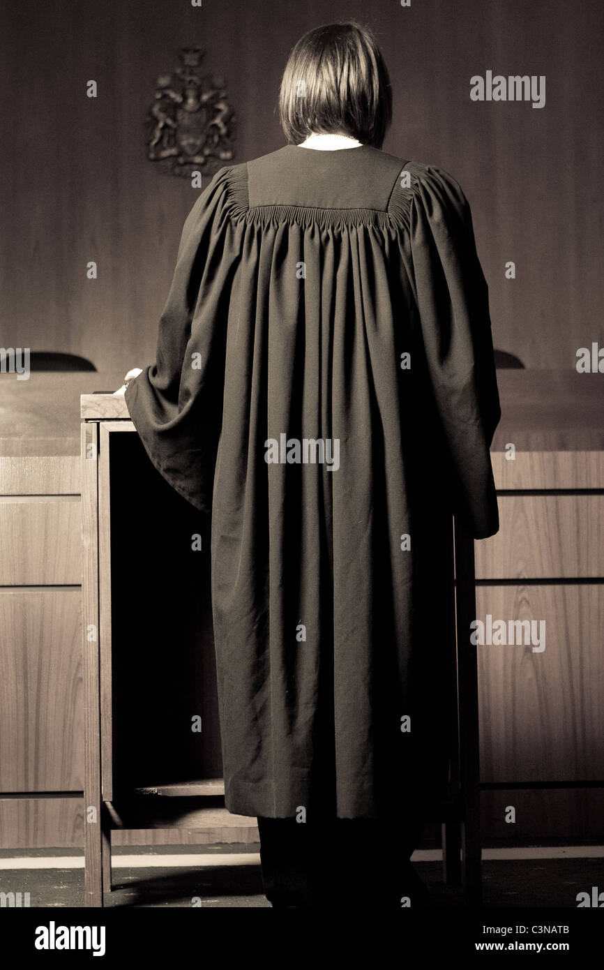 Female lawyer, acting as a barrister standing at podium in empty Canadian courtroom. Lawyer is gowned but not wigged. Stock Photo