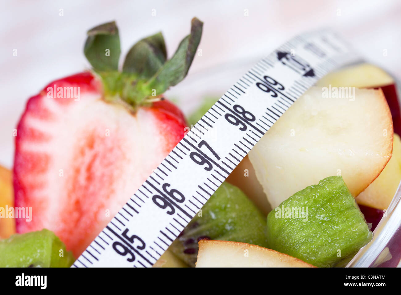 Fruit salad in white plate with measure tape, closeup Stock Photo