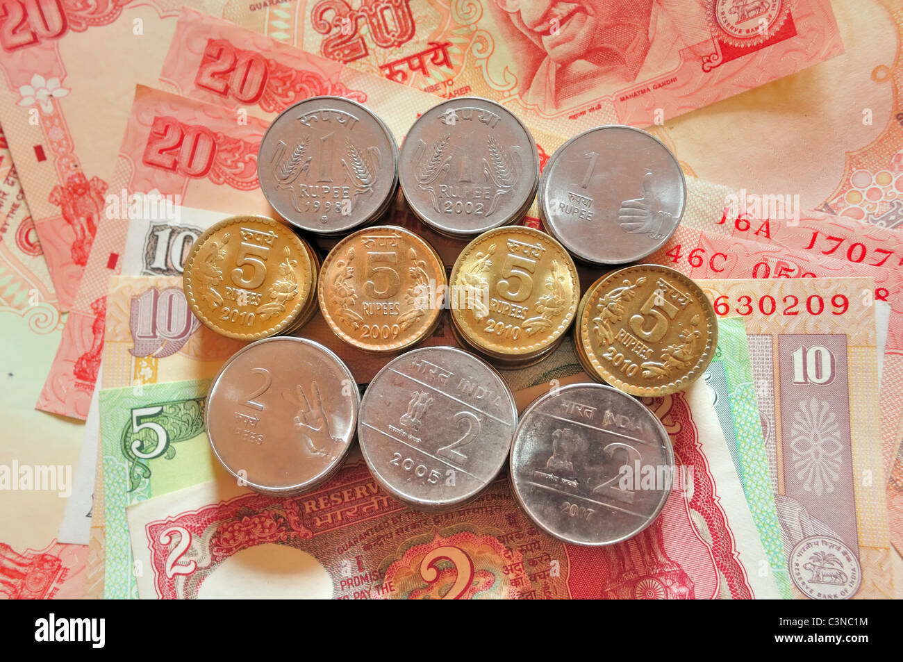 Stack of Indian currency coins on some Indian currency bank notes Stock Photo