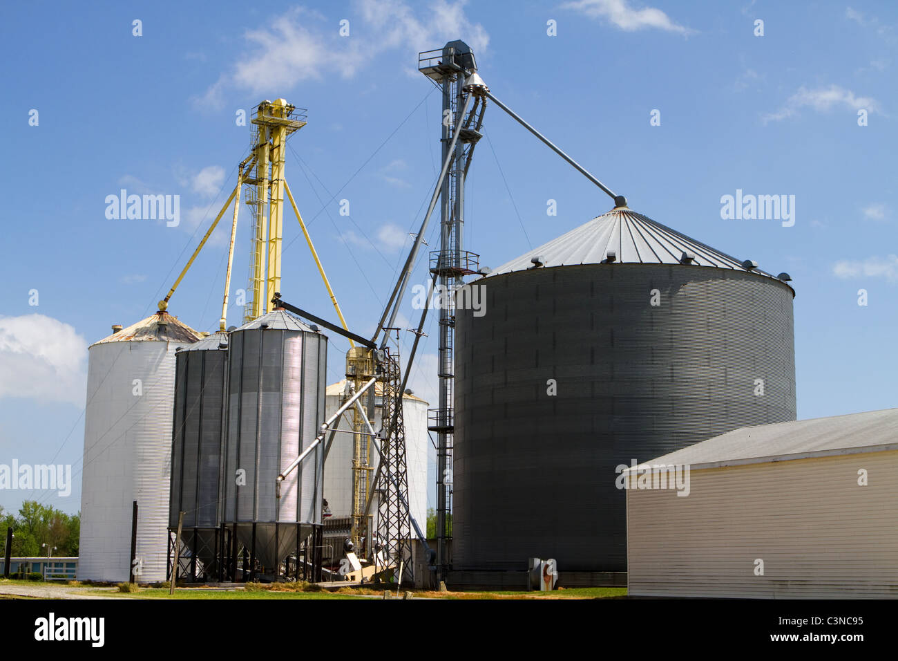 Grain storage elevators and silos for storing harvested crops against a blue sky. Stock Photo