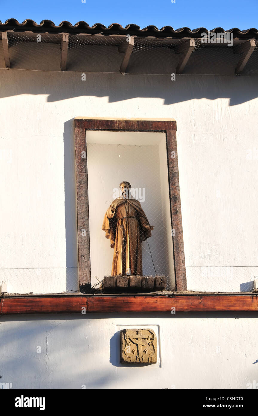Franciscan friar statue standing in a white alcove above the entrance ...
