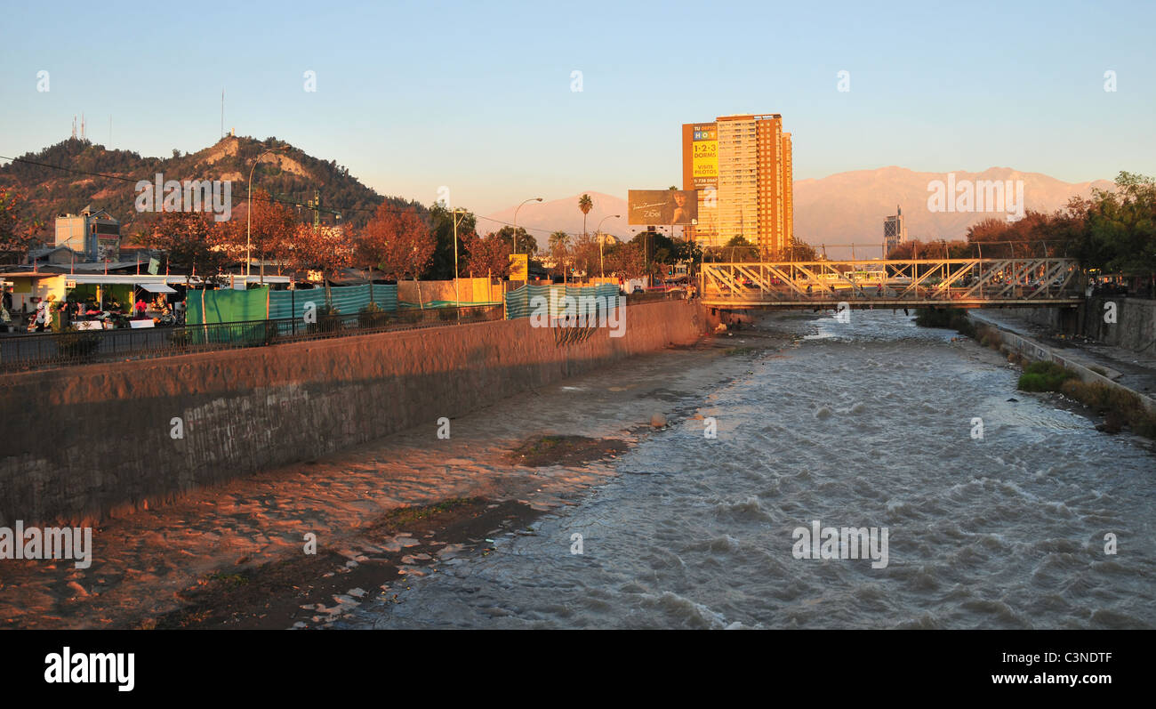 Blue sky evening sunlight view of Rio Mapocho, near Mercado Central,  towards Andes and San Cristobal Hill, Santiago, Chile Stock Photo