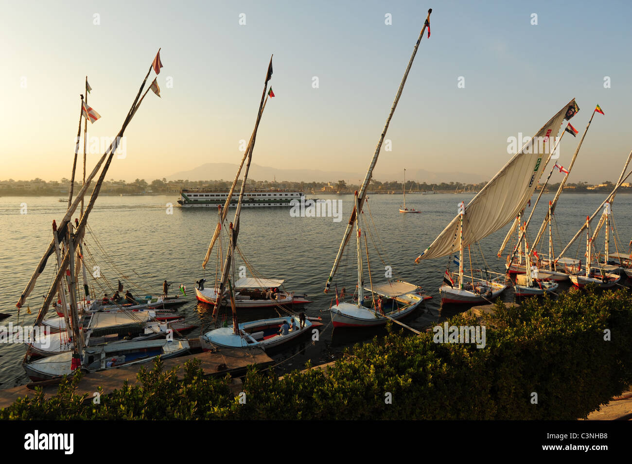 Africa Middle Eastern Egypt Egyptian Luxor Nile River feluccas felucas and a river cruise boat at sunset Stock Photo