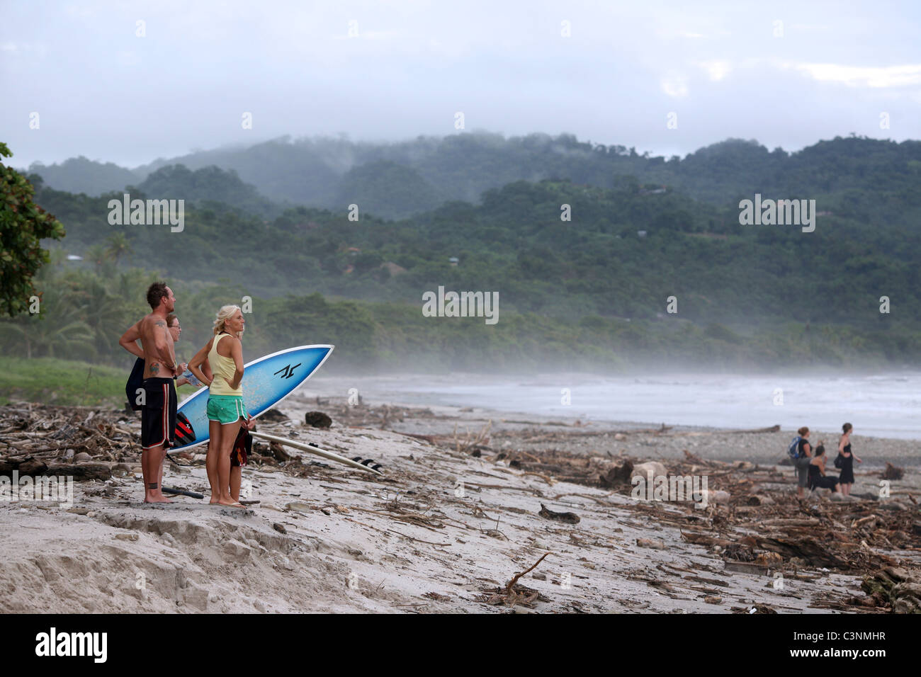 A group of travelers stand on the beach looking at the waves in Puntarenas, Costa Rica. Stock Photo