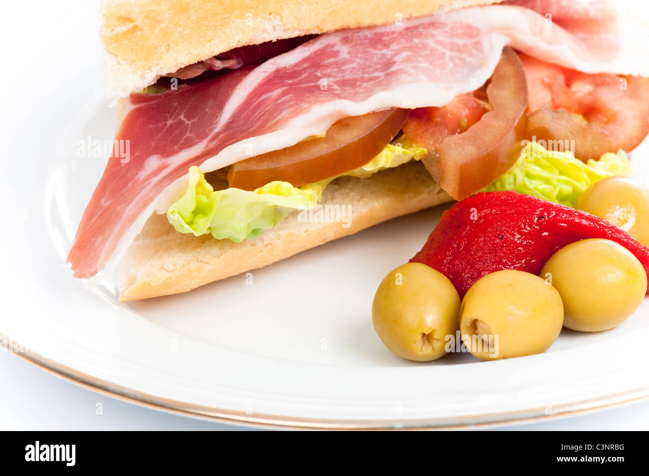 Baguette filled with serrano ham, lettuce and tomato, with a pepper and