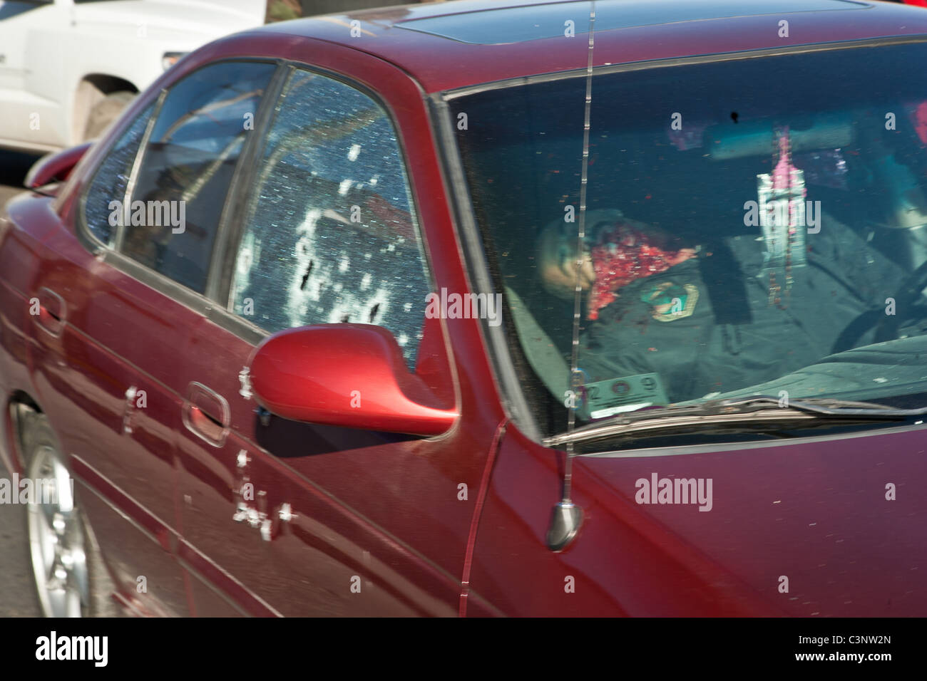 A former Juarez police officer lies dead behind the wheel of his car shot in the drug wars