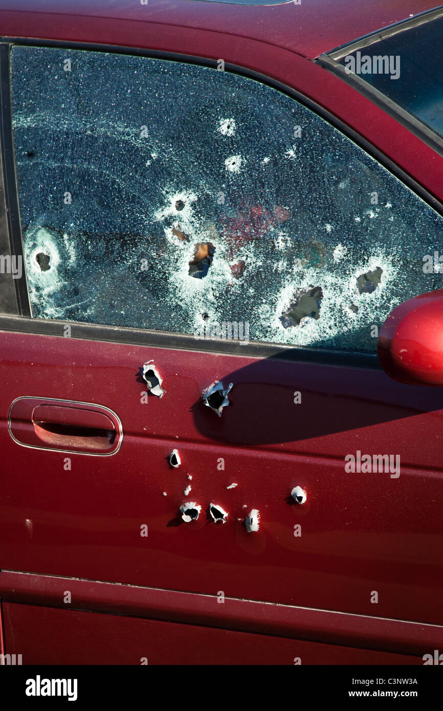 The bullet riddled window showing murder victims inside a vehicle during morning rush hour in Ciudad Juárez, Mexico. Moments earlier drug cartel assassins shot dead a policeman using automatic weapons at a traffic light in the downtown area. Stock Photo