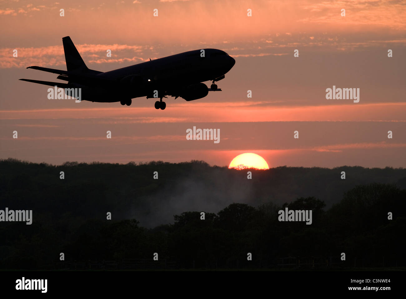 Aeroplane about to land, against setting sun. Stock Photo