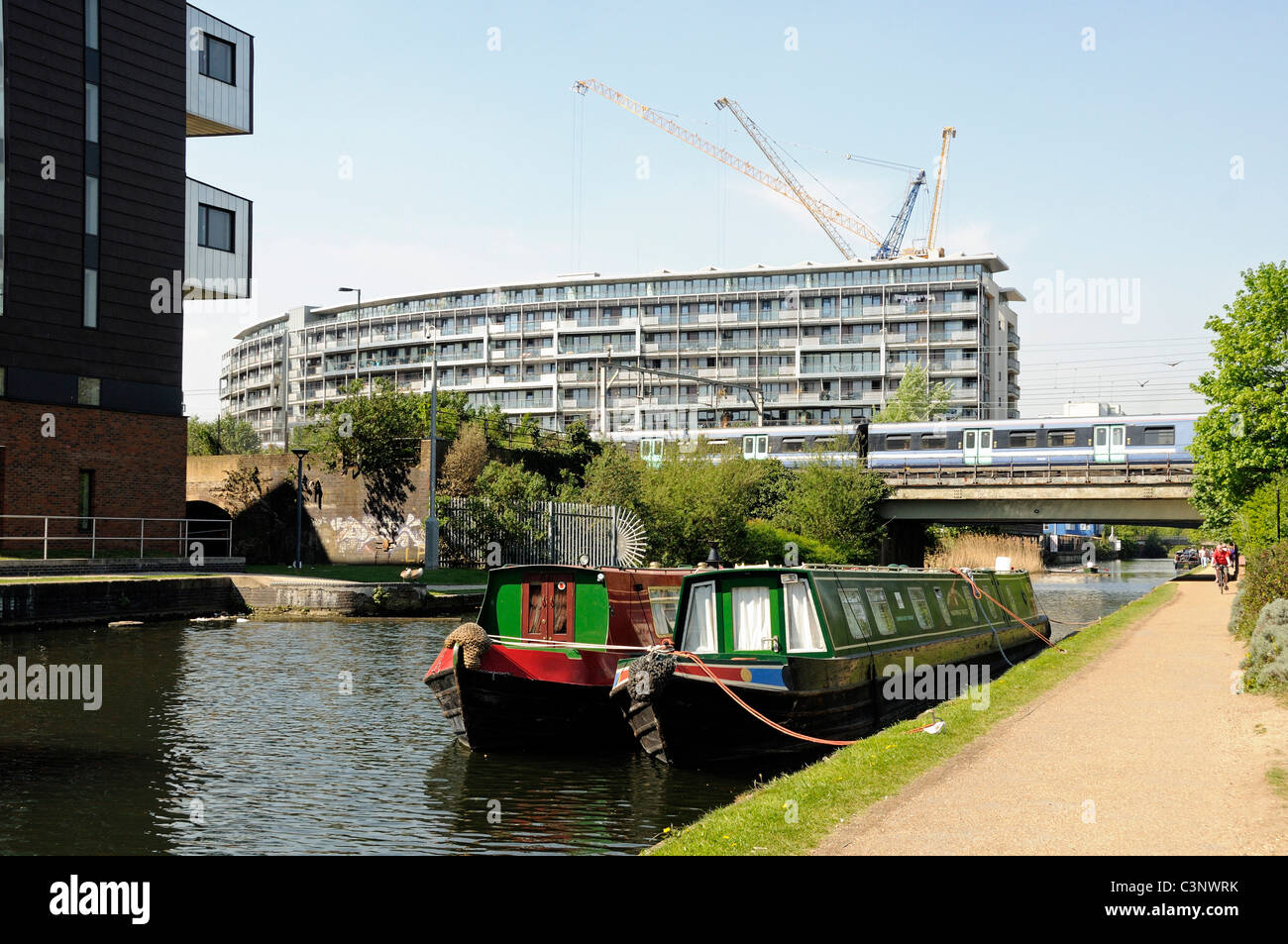 Houseboats on the Regent's Canal at Mile End with towpath showing and modern flats behind, London England UK Stock Photo