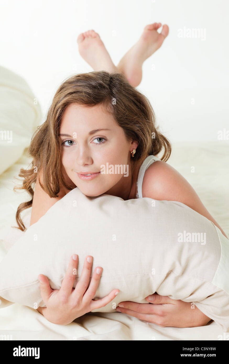 Pretty young woman in bed embracing pillow Stock Photo