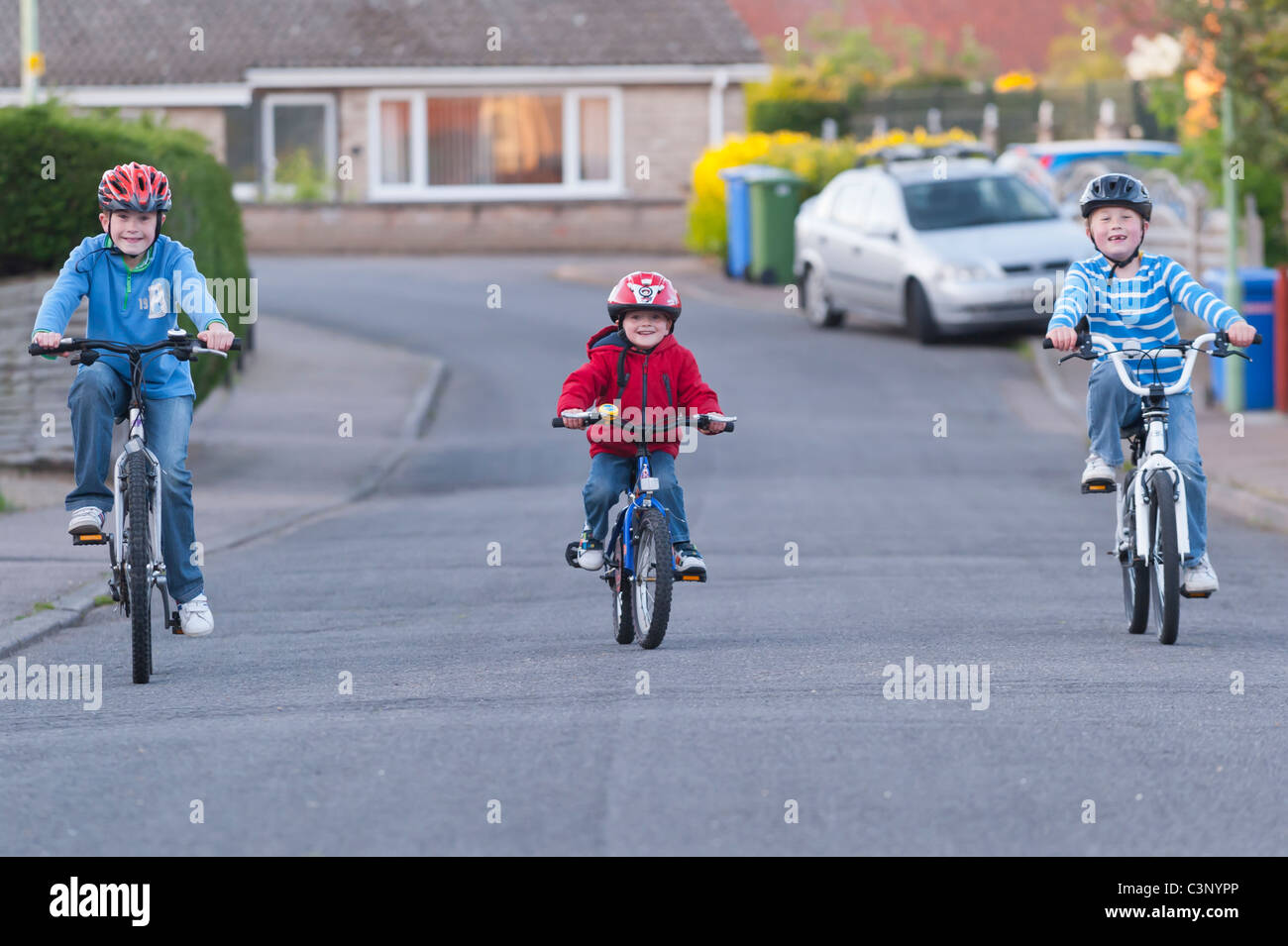 Three boys riding their bikes in a uk street Stock Photo