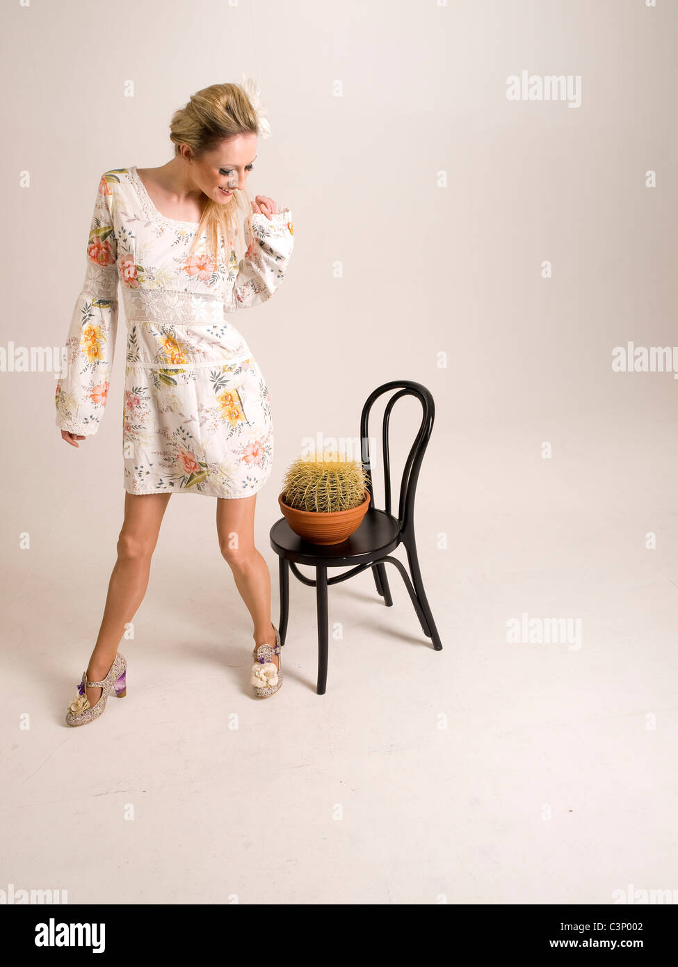 Amusing shot of attractive blond model pretending to sit on a cactus Stock Photo
