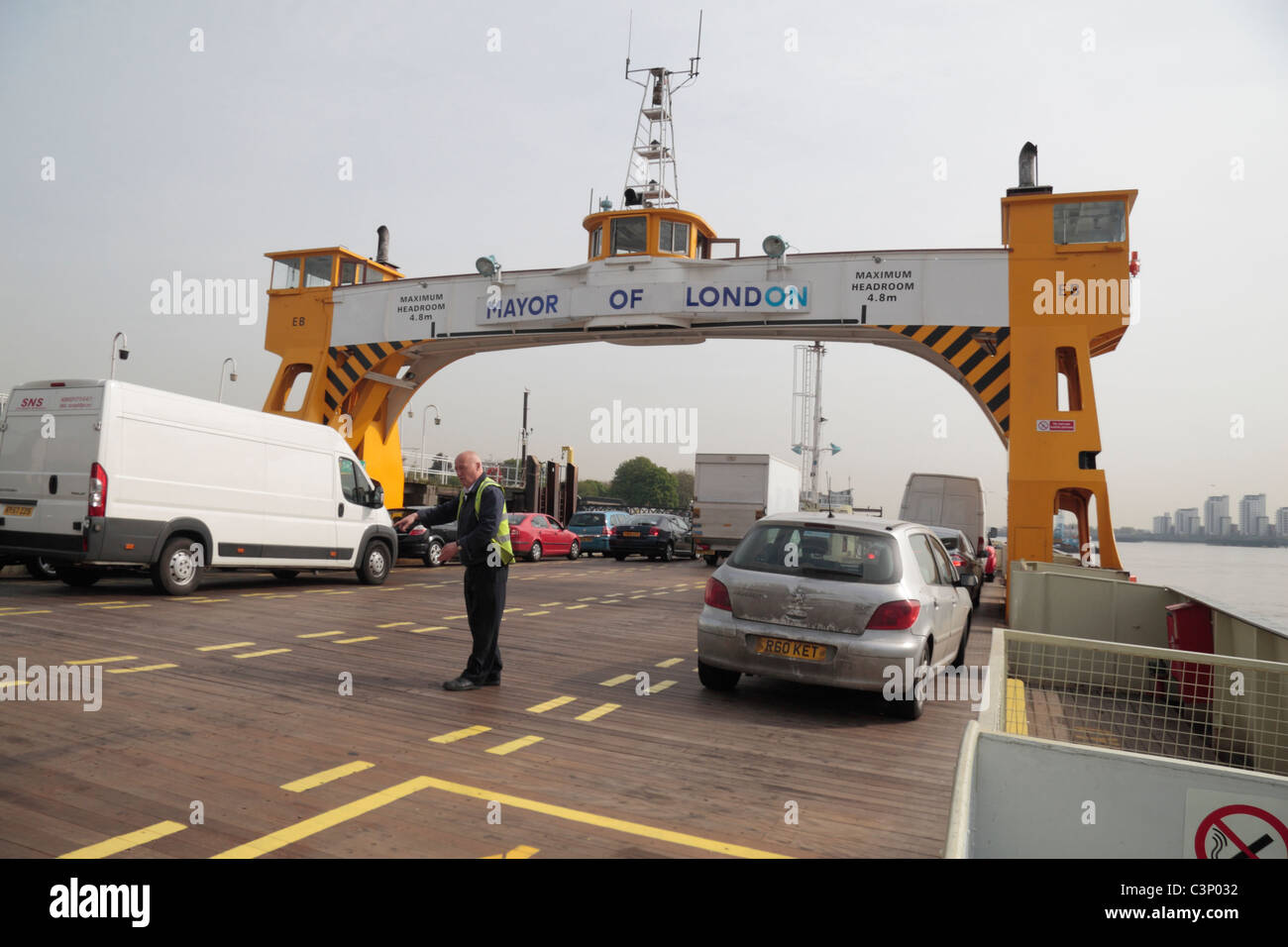Man loading cars and vans onto the 'James Newman' Woolwich Ferry, before it  crosses the River Thames, East London, UK. Stock Photo