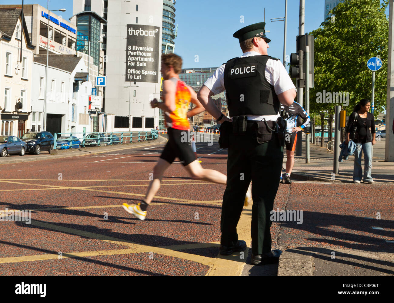 Runner runs past Police Officer Belfast Marathon Stock Photo